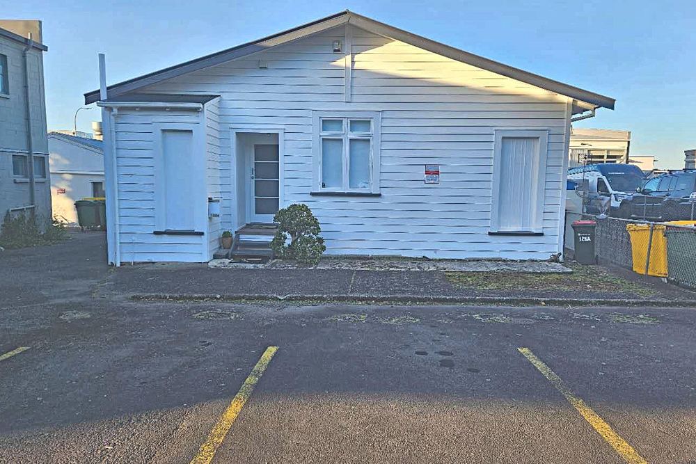 The white weatherboard building at 128A Kitchener Road, seen from the rear car park