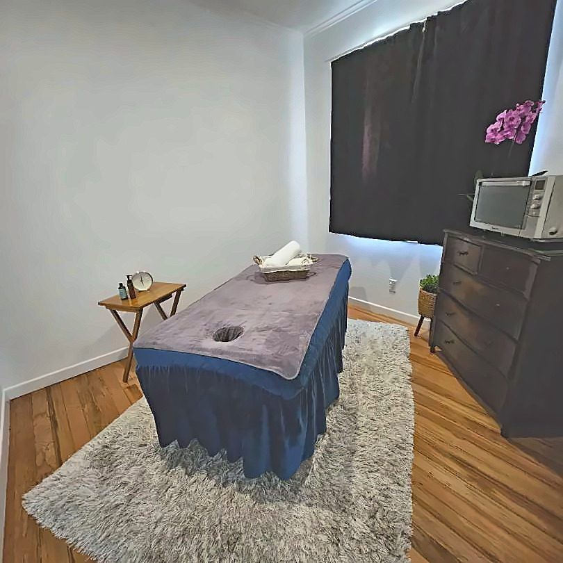 Treatment room at Shoreline Massage Milford with a massage table, soft rug and wooden floor